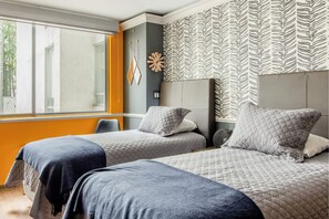 Ein Hotelzimmer mit zwei Betten, einem großen Fenster und zebra-gemustertem Wandpapier.
