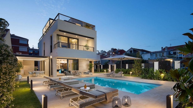 A modern two-story house with a swimming pool, outdoor seating, and a well-lit patio area. - Awesome home in Zadar (Zadar)