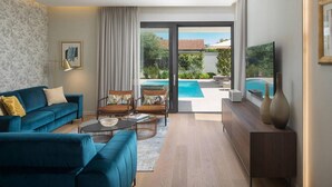 A modern living room with a blue sofa, a coffee table, and a view of a swimming pool through a glass door. - Awesome home in Zadar (Zadar)