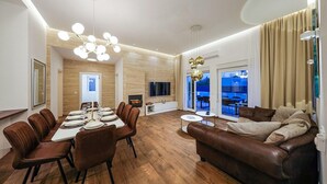 A modern living room with a dining area, a leather sofa, and a TV.