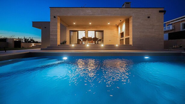 A modern house with a swimming pool in front.