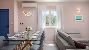 A modern dining area with a glass table, grey chairs, and a white floral centerpiece. - Beautiful home in Nin (Nin)
