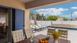 A balcony with a pool, lounge chairs, and a table with fruit and a vase. - Beautiful home in Nin (Nin)