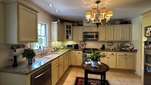A kitchen with light-colored cabinets, a central island, a chandelier, and a dining area with a table and chairs. - Charming 3 bedroom home  (Lewisburg)