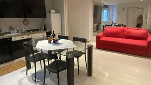 Une cuisine moderne avec un coin repas, un canapé rouge et un grand miroir.