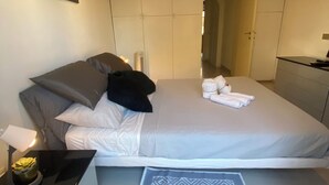 Une chambre moderne avec un grand lit, des tables de chevet, un bureau et un téléviseur fixé au mur.