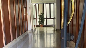 Un couloir aux murs recouverts de lambris en bois, une plante en pot et une porte dotée d’une poignée dorée.