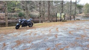 A paved area with a motorcycle parked near a signpost.