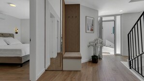 Un dormitorio moderno con cama, mesita de noche y tocador. Una escalera de madera conduce a otra habitación.