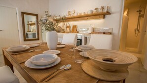 Ein Essbereich mit einem Holztisch, gedeckt für eine Mahlzeit, umgeben von weißen Stühlen.