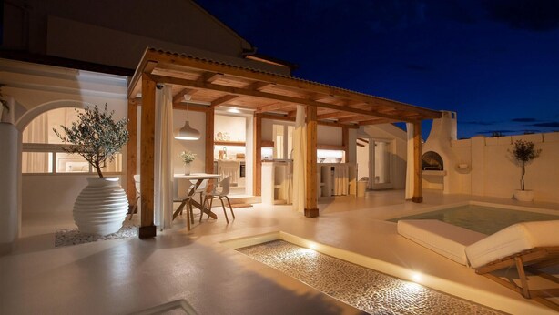 Ein moderner Außenbereich mit Patio, einer Pergola, einem Esstisch mit Stühlen, einem kleinen Pool und einem Topfpflanzen.