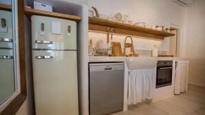 Eine Küche mit einem weißen Kühlschrank, einer Spülmaschine, einem Backofen und einem Holzregal über der Spüle.