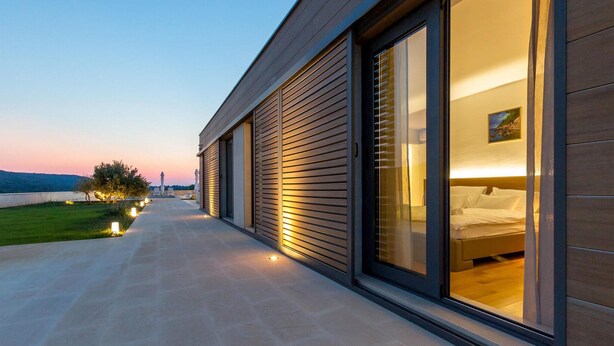 A modern hotel room with a large sliding glass door, a view of the sea, and a pathway leading to the entrance. - 5 bedroom gorgeous home in Hvar (Hvar)