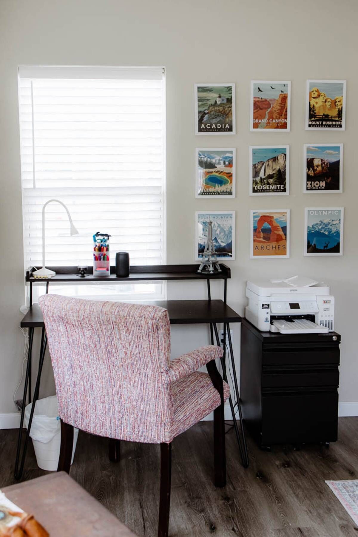 A home office with a desk, chair, printer, and wall art.