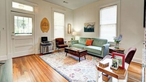 A living room with hardwood flooring, a green sofa, a coffee table, and a fireplace. - Tucked Inn fantastic location! (Memphis)