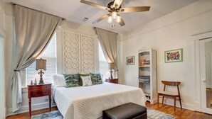A bedroom with a bed, a ceiling fan, a nightstand, a chair, and a bookshelf. - Tucked Inn fantastic location! (Memphis)
