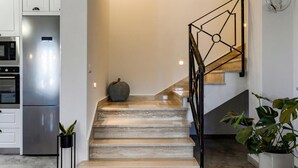 Eine minimalistische Treppe führt zu einer Zwischenebene mit einem Blumentopf.
