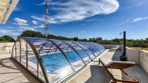 Ein Dachpool mit Glasveranda, Liegestühlen und einem Wasserspiel.