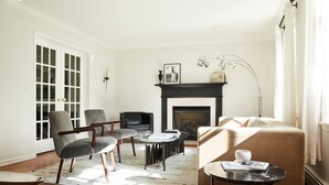 Un salon avec une cheminée, deux fauteuils, un canapé, une table basse et une table d’appoint.