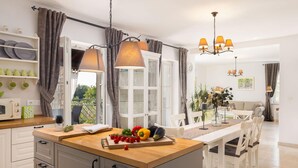 Una cocina moderna con encimera de madera, armarios abiertos y una zona de comedor con mesa y sillas.