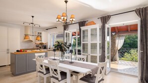Una cocina moderna con armarios blancos, encimera de madera y un comedor con mesa y sillas.