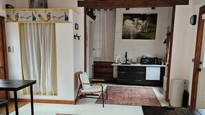 Olohuone on viihtyisä, ja siellä on sohva, sohvapöytä ja ruokapöytä. Keittiöalueella on pesuallas ja liesi. Huoneen katossa on ainutlaatuinen design ja seinällä taulu.