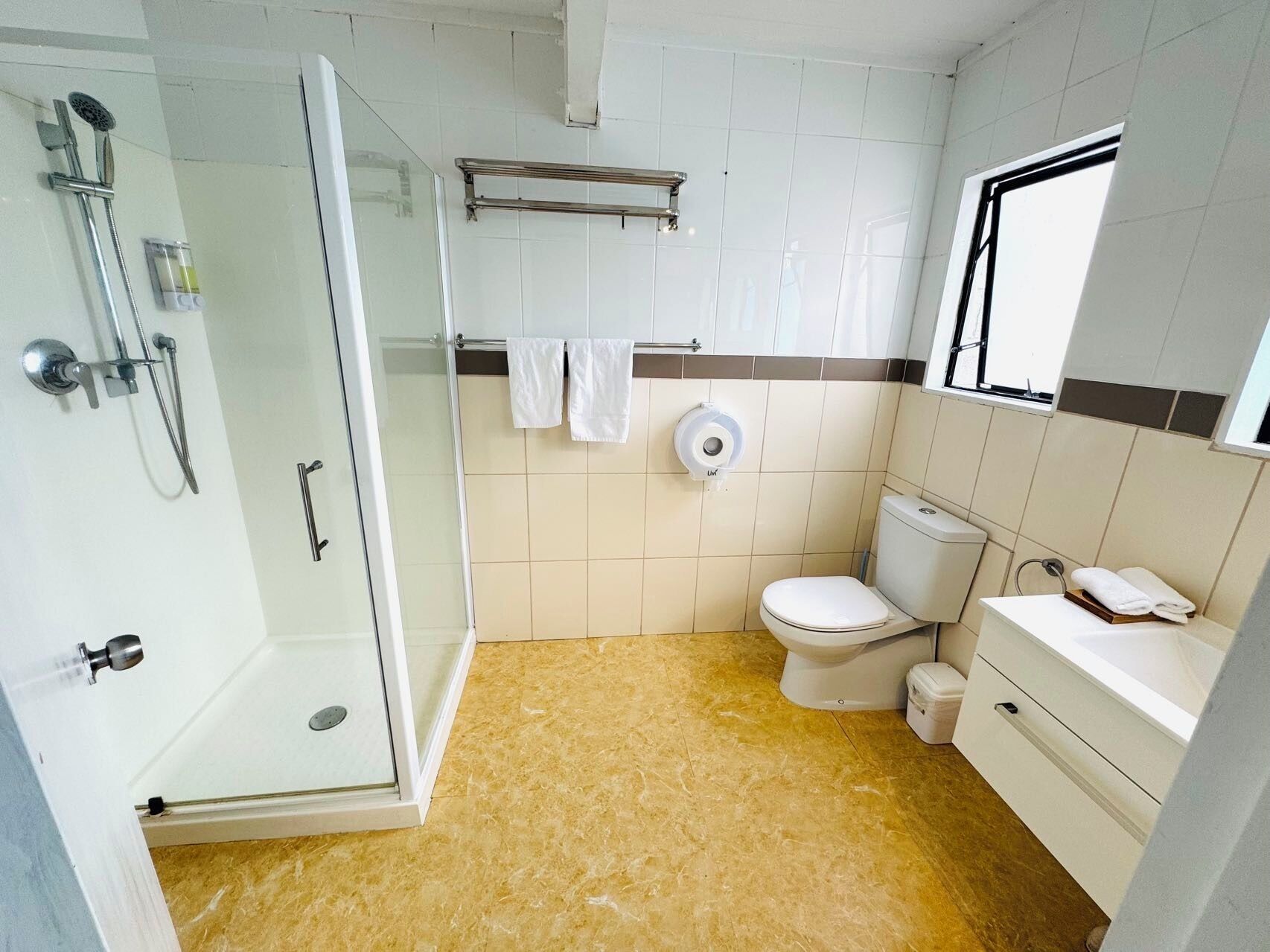 A bathroom with a glass-enclosed shower, a toilet, a sink, and a towel rack.