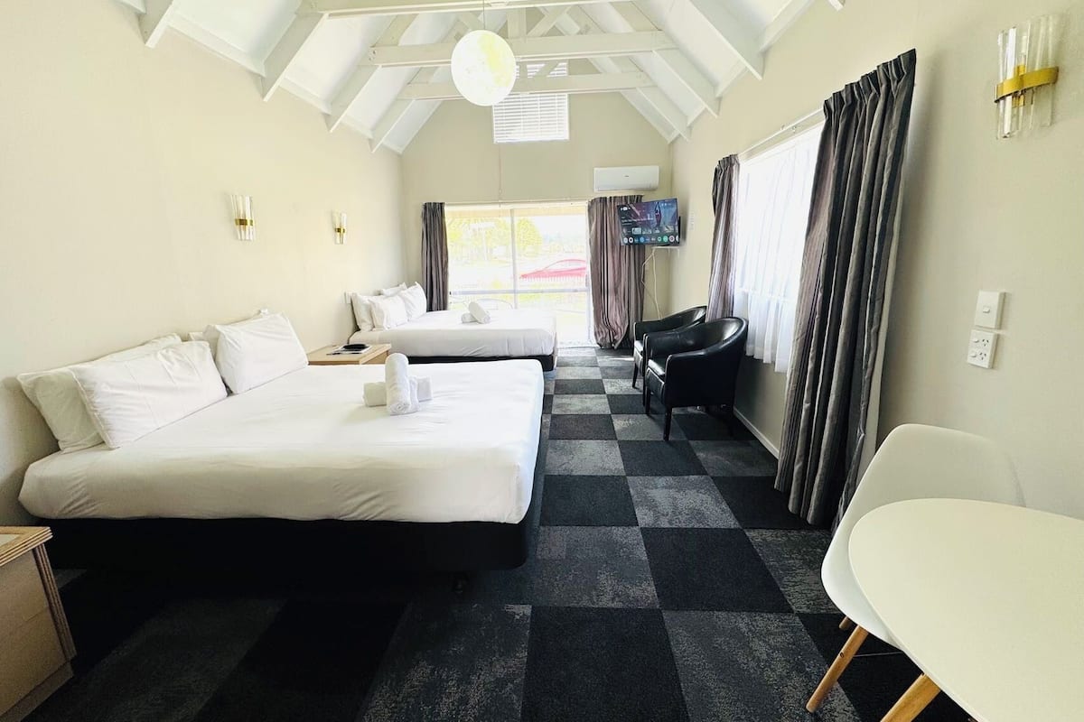Habitación de hotel con dos camas, televisión, escritorio y una silla.