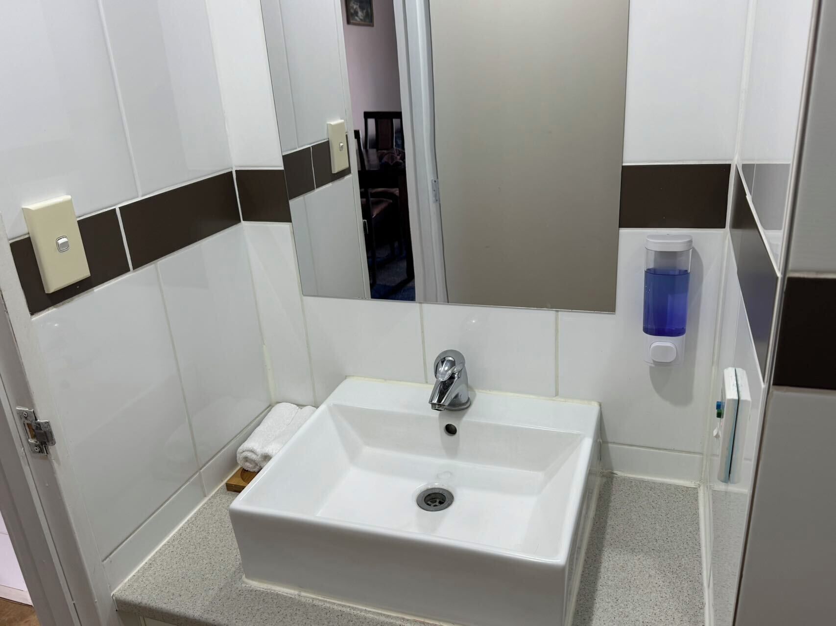 Une salle de bain avec un lavabo blanc, un miroir et un porte-serviettes.