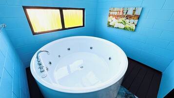Une salle de bain avec une grande baignoire, une fenêtre et un tableau au mur.