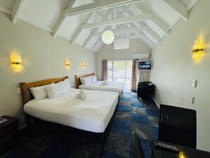 A hotel room with two beds, a TV, and a ceiling fan. - Apex on Fenton (Rotorua)