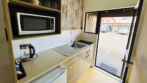 A compact kitchen with a microwave, kettle, and sink. - Apex on Fenton (Rotorua)
