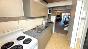 A compact kitchen with a stove, sink, and cabinets. - Apex on Fenton (Rotorua)