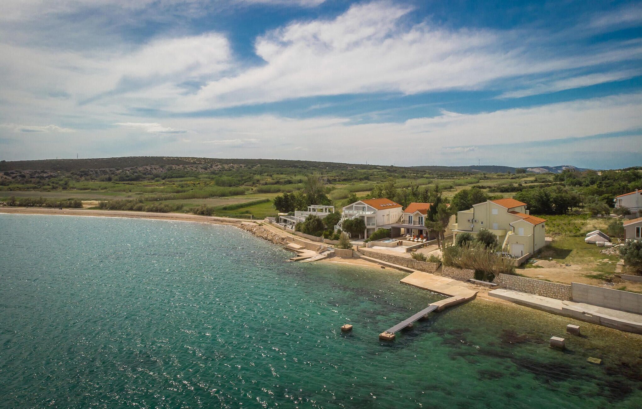 A coastal property with houses near a beach, a clear sky, and a calm sea.