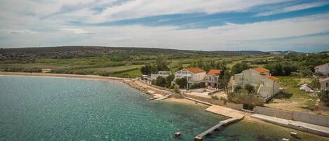 A coastal property with houses near a beach, a clear sky, and a calm sea.