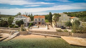A coastal property with multiple buildings, a swimming pool, and a stone retaining wall. - Lovely home in Novalja with WiFi (Novalja)
