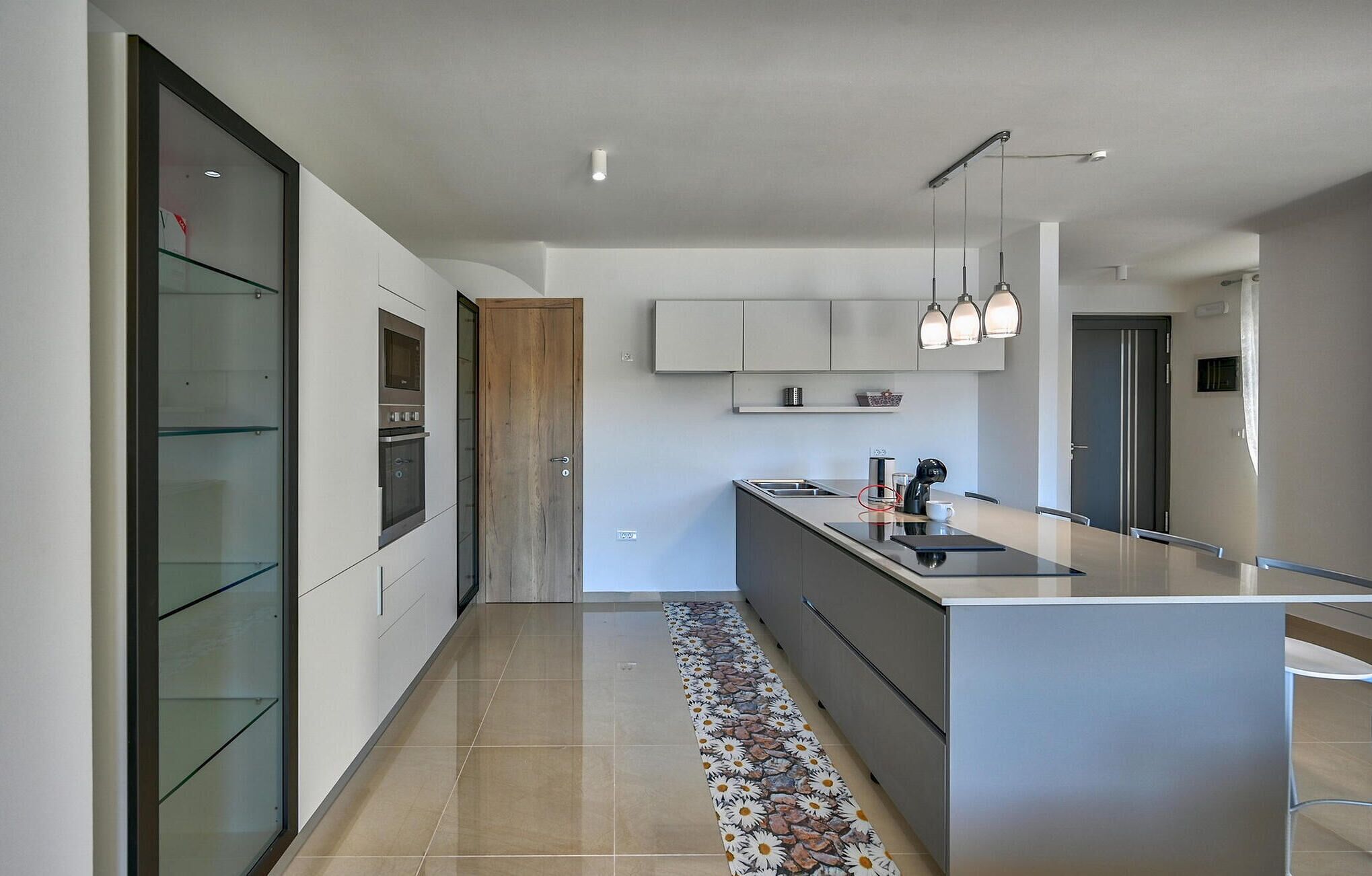Een moderne keuken met een centraal eiland, roestvrijstalen apparatuur en hanglampen.