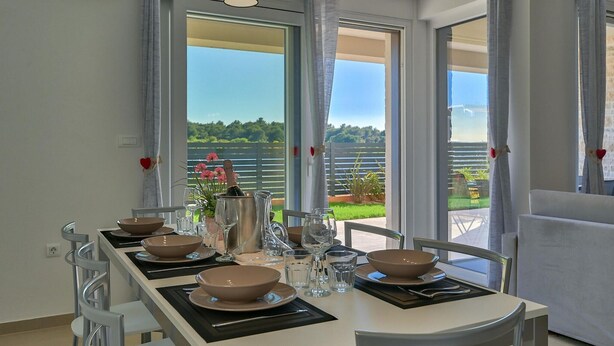Un coin repas avec une table dressée pour six personnes, offrant une vue panoramique sur le paysage extérieur.
