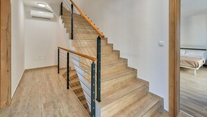 Eine Treppe mit Holzstufen und Metallgeländern, die zu einem Schlafzimmer mit Bett und Nachttisch führt.