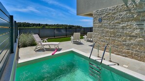 Ein Pool auf dem Dach mit einer Steinmauer und Blick auf einen Wald.