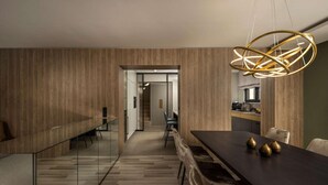 A modern dining area with a long table, chairs, and a unique pendant light.