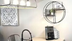 Eine Küche mit Spüle aus Edelstahl, einer Kaffeemaschine und einem Schild mit der Aufschrift 'HAPPINESS'.