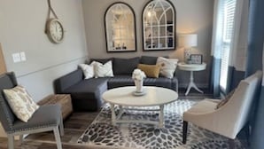 Ein Wohnzimmer mit einer Couch, Sesseln, einem Couchtisch und einem gemusterten Teppich.