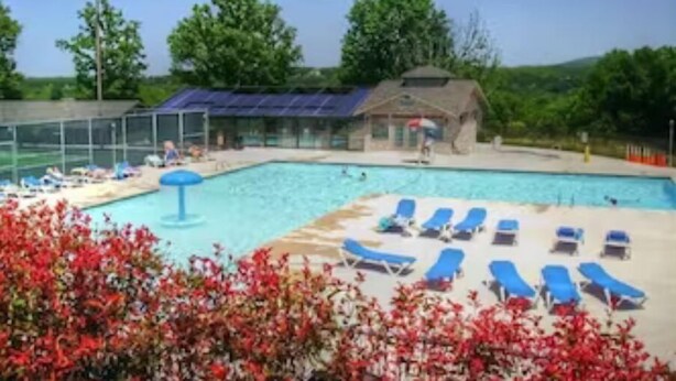 Ein Swimmingpool mit blauen Liegestühlen und einem überdachten Bereich mit Solarmodulen.
