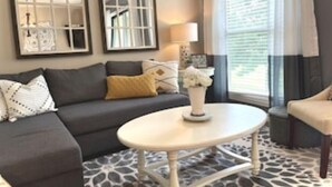 Ein Wohnzimmer mit einer Couch, einem runden Couchtisch und zwei Rundbogenfenstern.