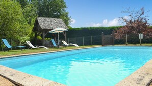 Une piscine avec des chaises longues et une structure en bois en arrière-plan.