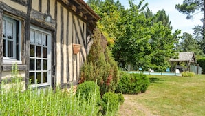 Une maison traditionnelle à colombages, dotée d’un jardin bien entretenu, d’un petit étang et d’un belvédère.