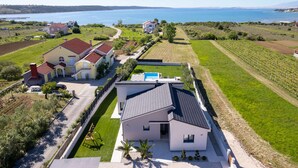 Een modern huis met zwembad, omringd door een wijngaard en uitzicht op de kust.