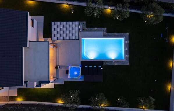 A rooftop swimming pool with a hot tub and a seating area.