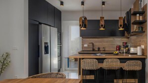Una cocina moderna con una isla central, taburetes de bar y una mesa de comedor.